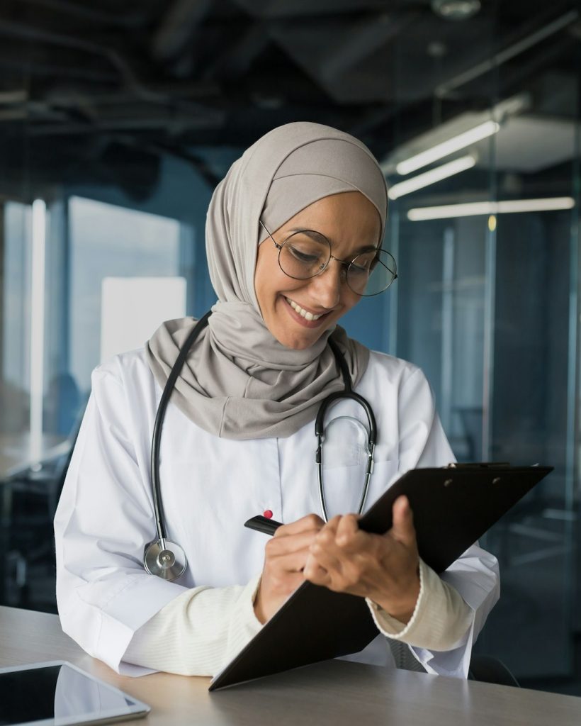 A young Arab female doctor, a Muslim woman, sits in the office. Works with documents